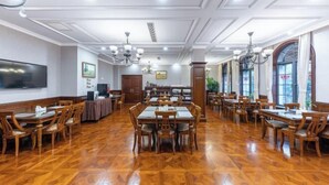 A spacious dining area with multiple wooden tables and chairs, a large flat-screen TV, and decorative lighting fixtures. - Jiade Hotel Chengdong Road (Yongkang)