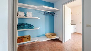 A room with a blue wall, white shelves, and a tiled floor. - Peaceful Apartment Surrounded by Nature – Quiet Location Minutes from Assisi (Pian della Pieve)