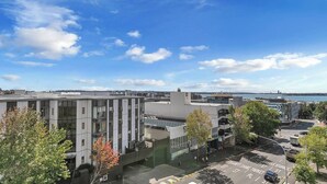 Un bâtiment moderne doté d’une façade en verre, d’un parking et offrant une vue sur la mer.
