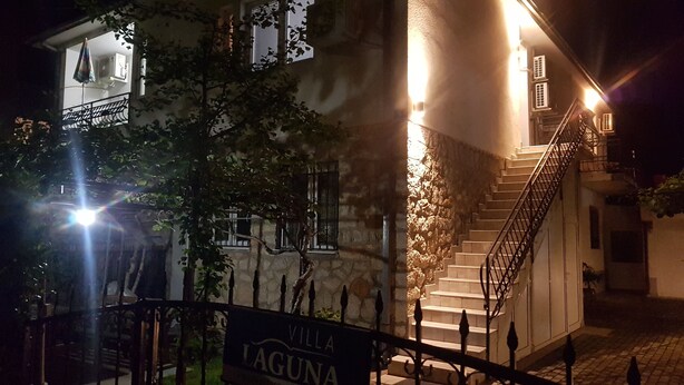 Un bâtiment doté d’un escalier menant à un balcon, d’une enseigne indiquant « VILLA LAGUNA » et d’une entrée bien éclairée.