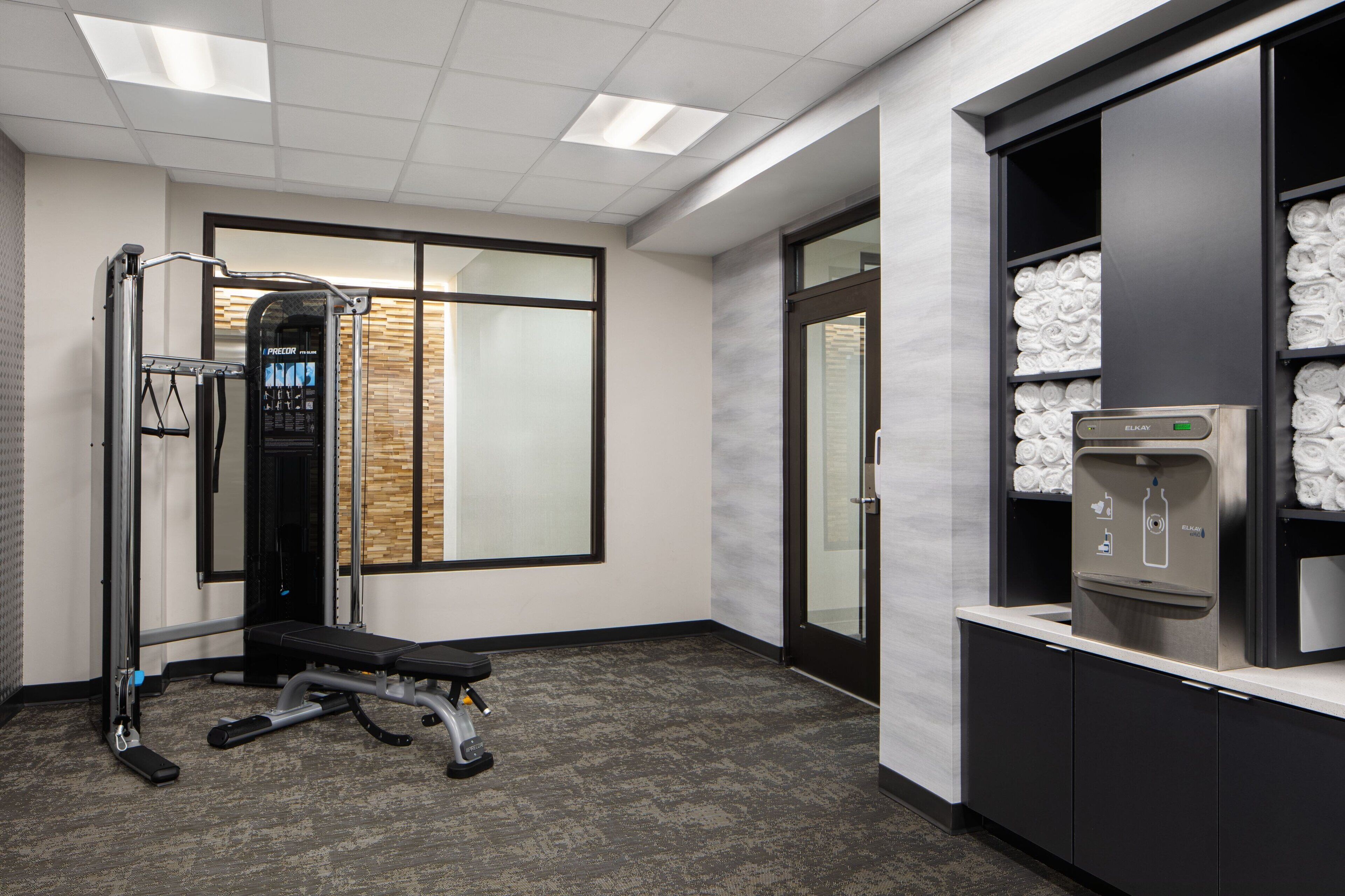 A gym with exercise equipment, a water dispenser, and a wall with a towel rack.
