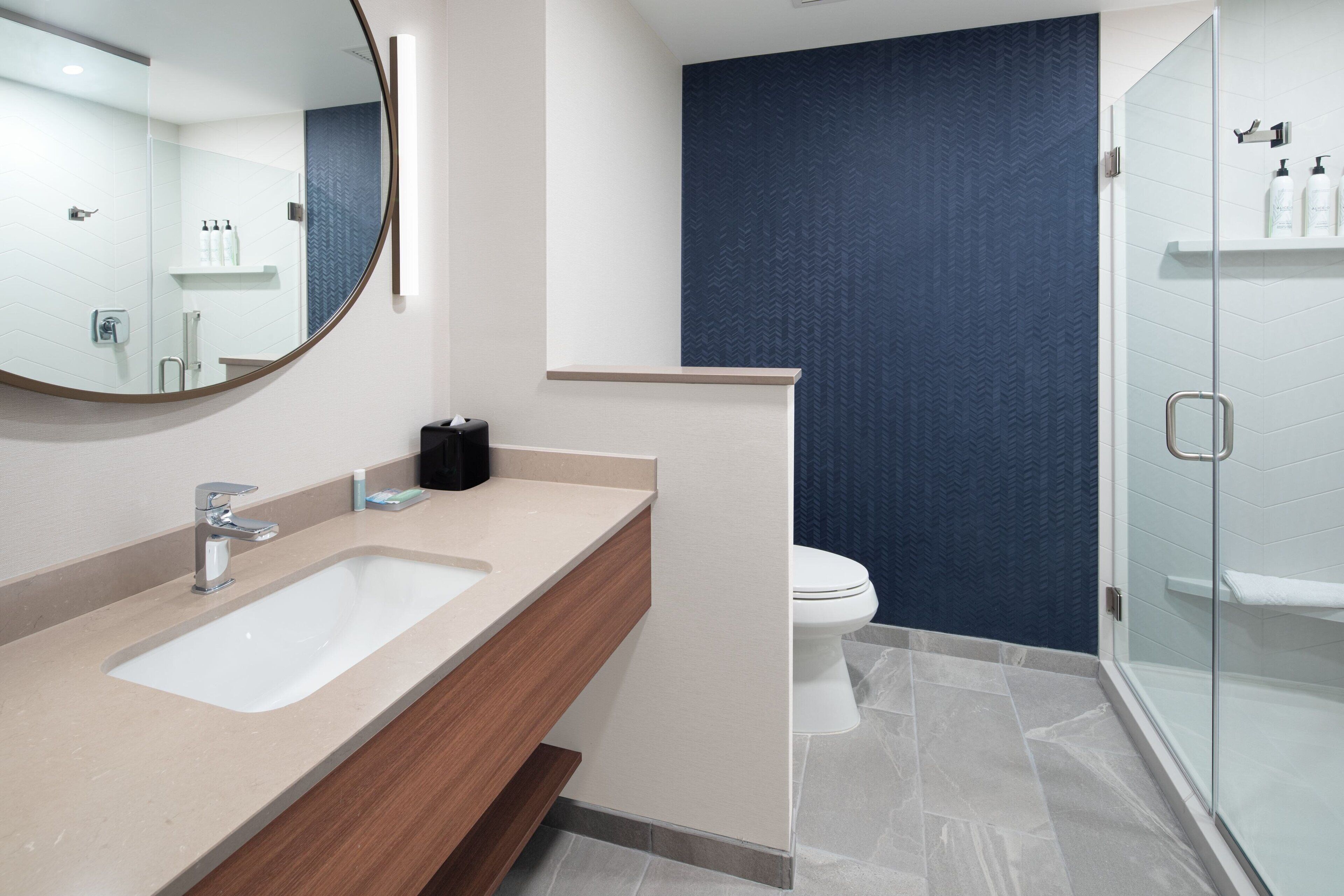 Une salle de bain moderne dotée d’un meuble-lavabo à deux vasques, de toilettes et d’une douche à parois de verre.
