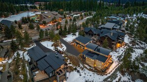 Un resort con diversi edifici, una seggiovia e un lago, circondato da montagne innevate.
