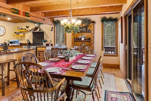 A wooden dining room with a large table set for six, surrounded by wooden chairs.