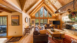 Un salon spacieux doté d’une grande cheminée, de poutres apparentes en bois et d’un coin salon confortable.