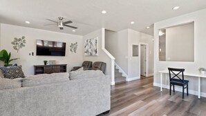 A modern living room with a grey sofa, a TV, and a ceiling fan. - 2 MASTER BEDROOMS! 4 Bed 4 Bath Townhome (Washington)