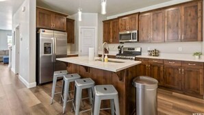 A modern kitchen with wooden cabinets, stainless steel appliances, and a central island with stools. - 2 MASTER BEDROOMS! 4 Bed 4 Bath Townhome (Washington)