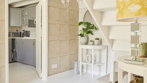 Une cuisine moderne avec des meubles gris, un plan de travail blanc et un mur recouvert de panneaux en bois.