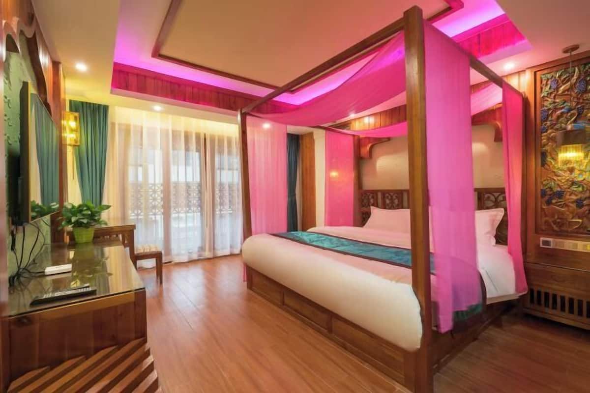 A four-poster bed with a canopy, a glass desk, and a wooden floor.