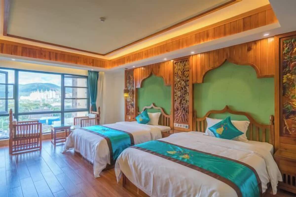 A hotel room with two beds, wooden headboards, and a large window offering a view of the city.