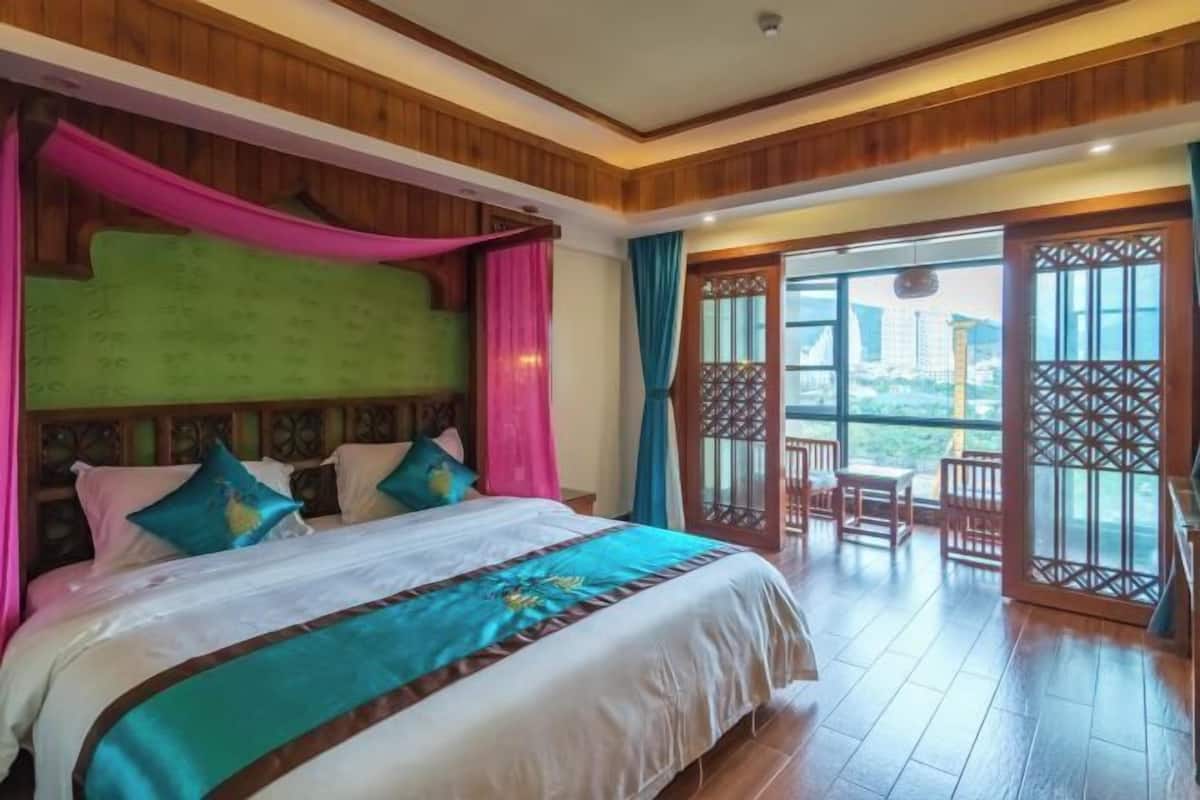 A hotel room with a bed, wooden paneling, a balcony with a view, and a traditional gate.