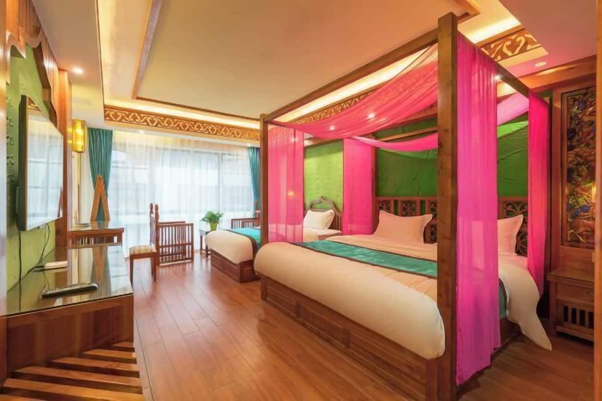 A four-poster bed with a canopy, a wooden floor, a desk with a chair, and a window with curtains.