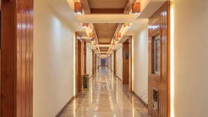 A long, well-lit hallway with wooden paneling and marble flooring, leading to a series of doors. - Lanmei Riverside Holiday Hotel (Jinghong)