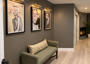 Un intérieur moderne avec un canapé vert, des œuvres d’art encadrées accrochées au mur et une cheminée.