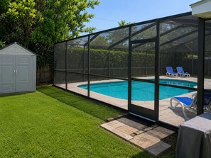 Un jardin avec une piscine, un patio couvert et un petit abri de jardin.