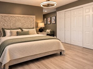 Une chambre à coucher avec un grand lit, une tête de lit ornée de sculptures complexes, une table de chevet avec une lampe et une armoire à portes doubles.