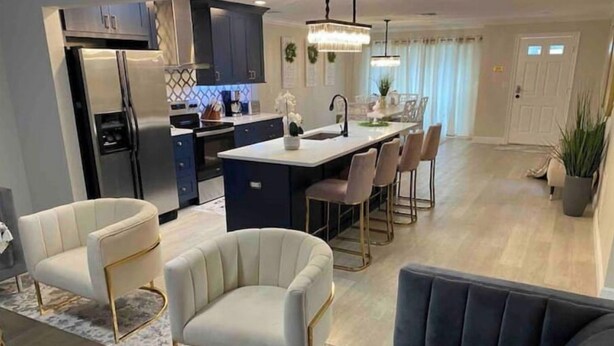 A modern kitchen with dark cabinets, a central island, and a dining area with chairs. -  HOT TOB HEATED POOL HOUSE, MINUTES FROM CLEARWATER BEACH (Clearwater)