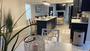 A modern kitchen with a central island, a dining area with chairs, and a living space with a fireplace. -  HOT TOB HEATED POOL HOUSE, MINUTES FROM CLEARWATER BEACH (Clearwater)