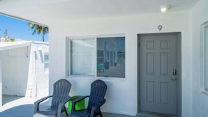 Un espace extérieur abrité comprenant deux chaises, une fenêtre et une porte.