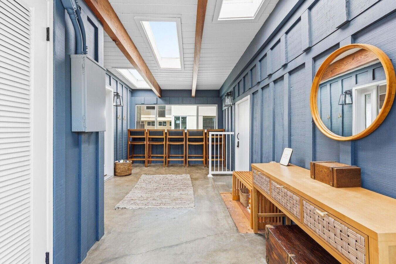 A room with a skylight, wooden chairs, a bench, and a mirror on the wall.