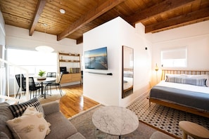Quarto moderno com cama, área de refeições e cozinha.