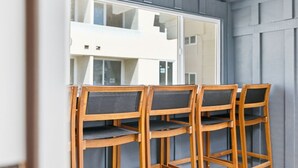 A balcony with four wooden chairs and a glass door.
