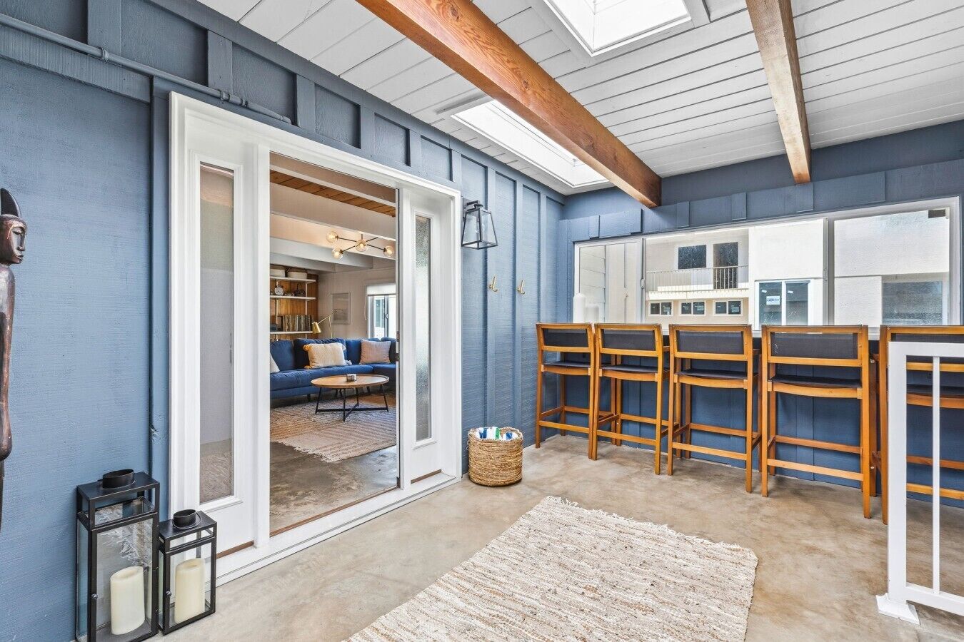 A room with a blue wall, a wooden ceiling beam, a sofa, a coffee table, and a rug.
