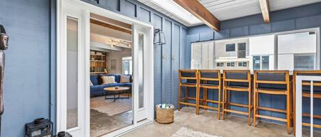 A room with a blue wall, a wooden ceiling beam, a sofa, a coffee table, and a rug.