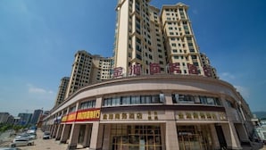 A hotel with a curved facade, multiple floors, and a prominent entrance with glass doors. - Jinchi Business Hotel (Jiangmen)