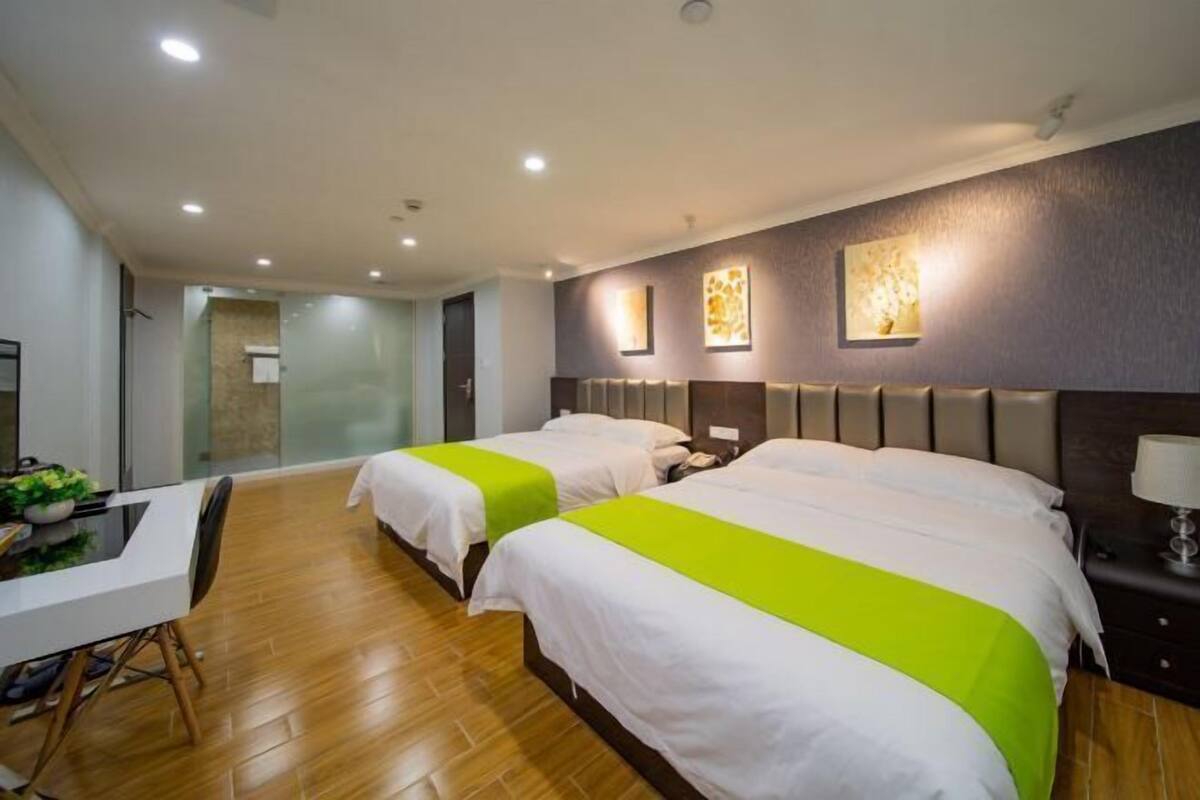 Een hotelkamer met twee bedden, een bureau en een douchehoek.
