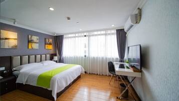 A hotel room with a bed, desk, and chair, a television, and artwork on the wall.