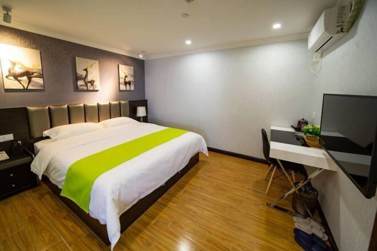 Een hotelkamer met een bed, een bureau, een stoel en kunst aan de muur.