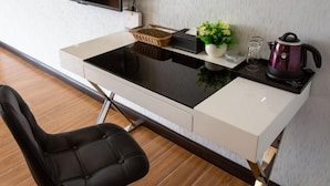 A modern kitchen with a built-in stove, a black chair, a small potted plant, and a kettle. - Jinchi Business Hotel (Jiangmen)