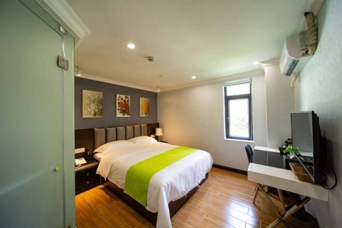Een hotelkamer met een bed, bureau en raam.