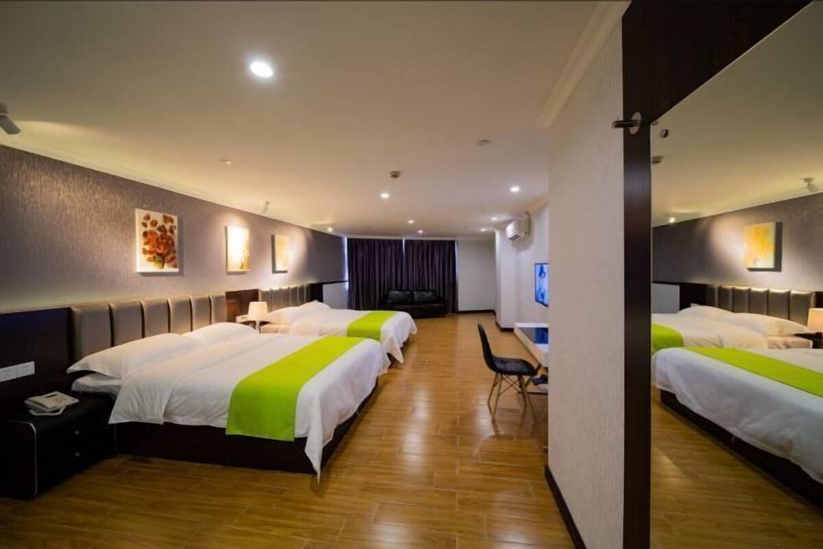 Een hotelkamer met drie bedden, een bureau en een stoel.