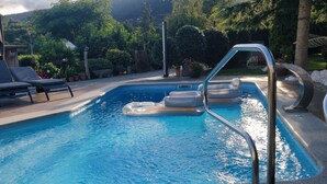 A swimming pool with lounge chairs and a poolside area surrounded by greenery. - Barranqueiro House (Vilaboa, Pontevedra)