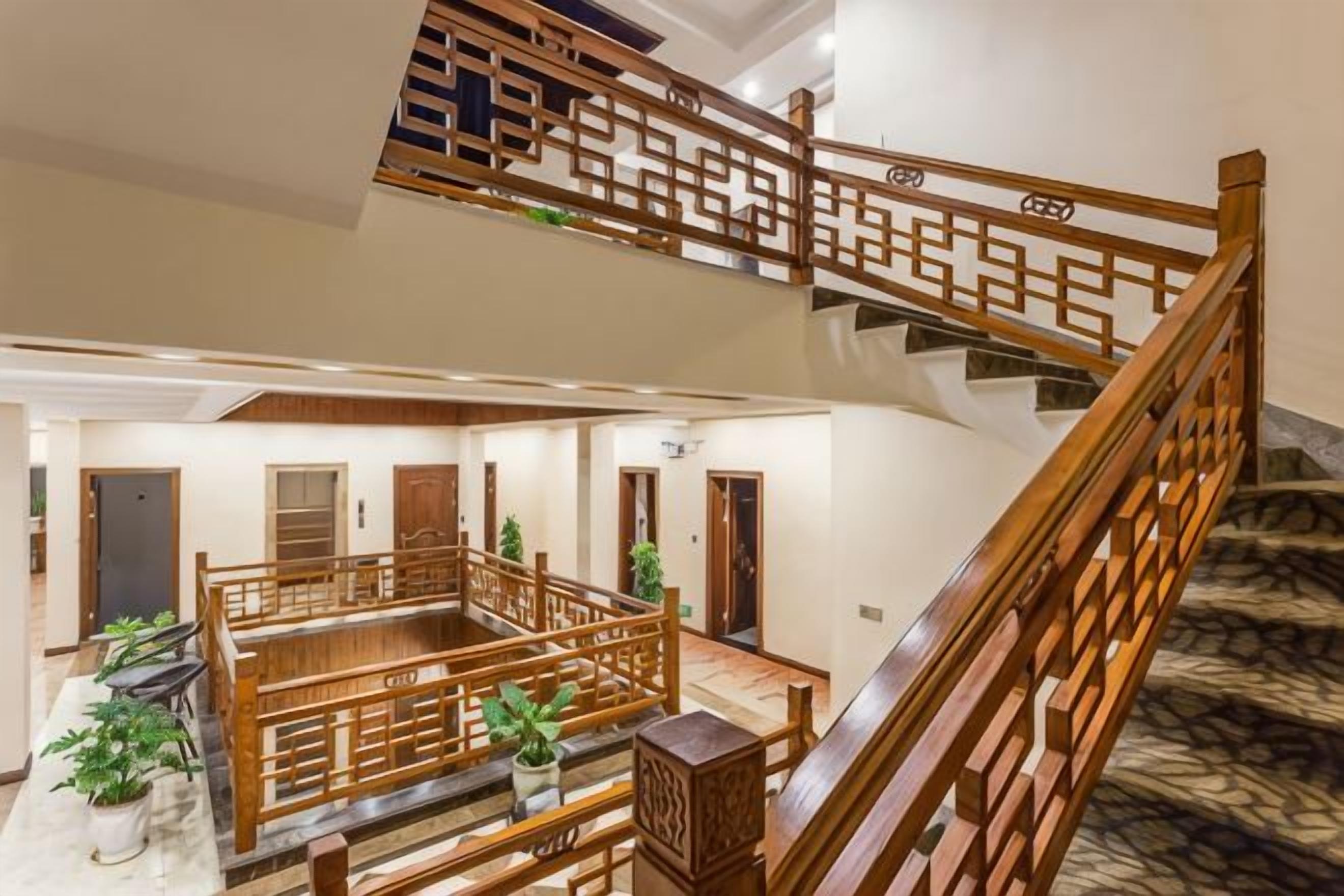 Una escalera de madera de varios niveles con un diseño tradicional, que conduce a un amplio piso superior con vistas del nivel inferior.