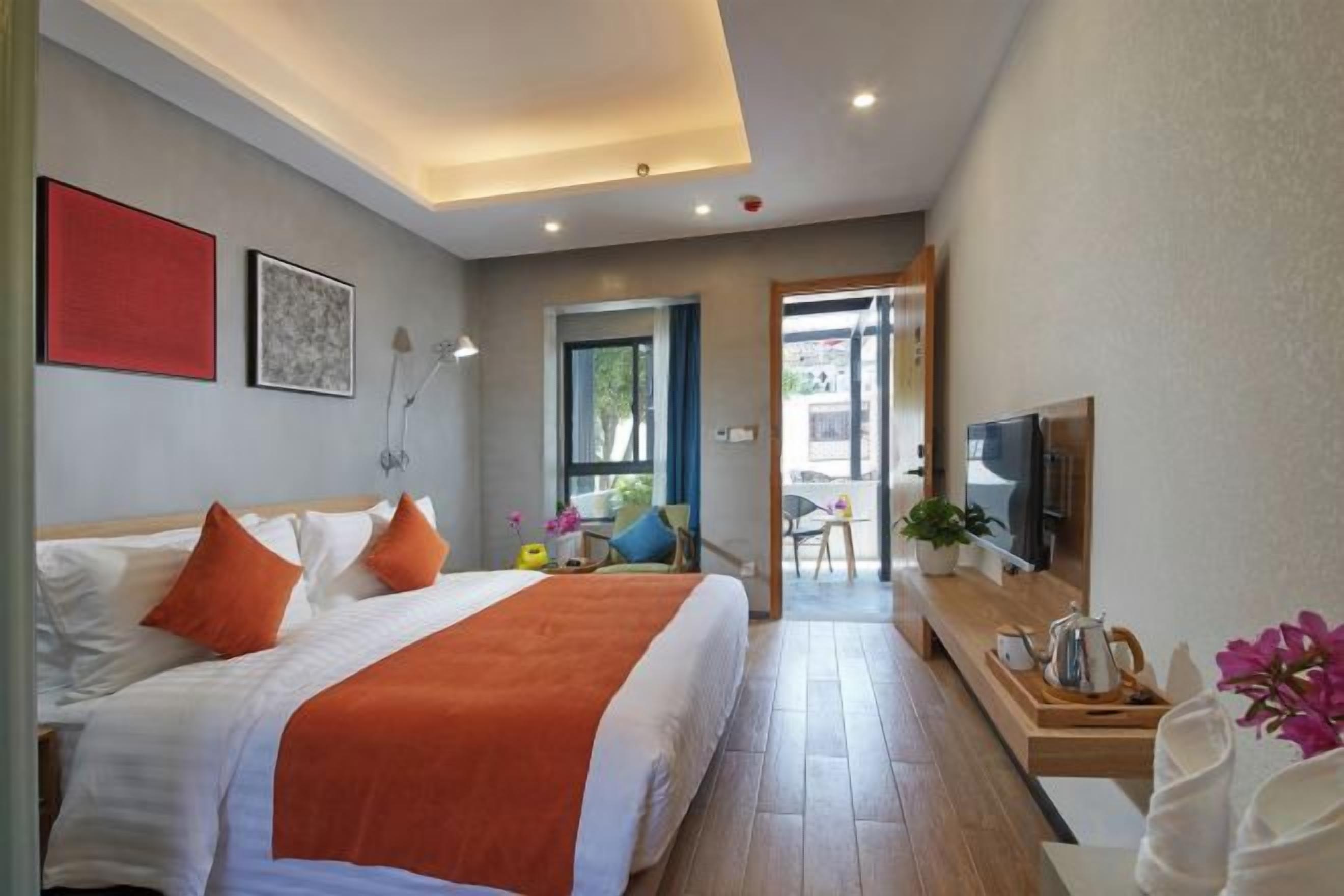 A hotel room with a bed, a TV, a desk, and a view of the outside.