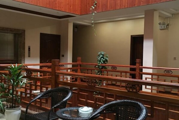 A hotel lobby with a wooden railing, chairs, and a potted plant. - Shuimoxuan Hotel (Tongxiang)