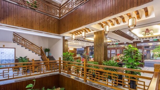 A multi-level wooden interior with a staircase, railings, and indoor plants.