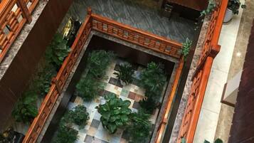 A courtyard with a checkered floor, surrounded by plants and a wooden fence.