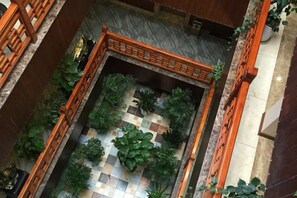 A courtyard with a checkered floor, surrounded by plants and a wooden fence. - Shuimoxuan Hotel (Tongxiang)
