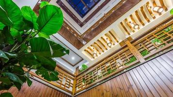 A multi-level wooden interior with a staircase, wooden railings, and a large plant.