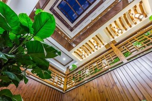 Un intérieur à plusieurs niveaux, avec une structure en bois, un escalier, des rampes en bois et une grande plante.