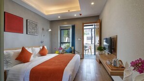 A modern hotel room with a large bed, a TV, and a small table with a kettle.