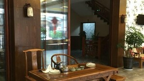 A wooden dining table with chairs, a potted plant, and a staircase in the background.