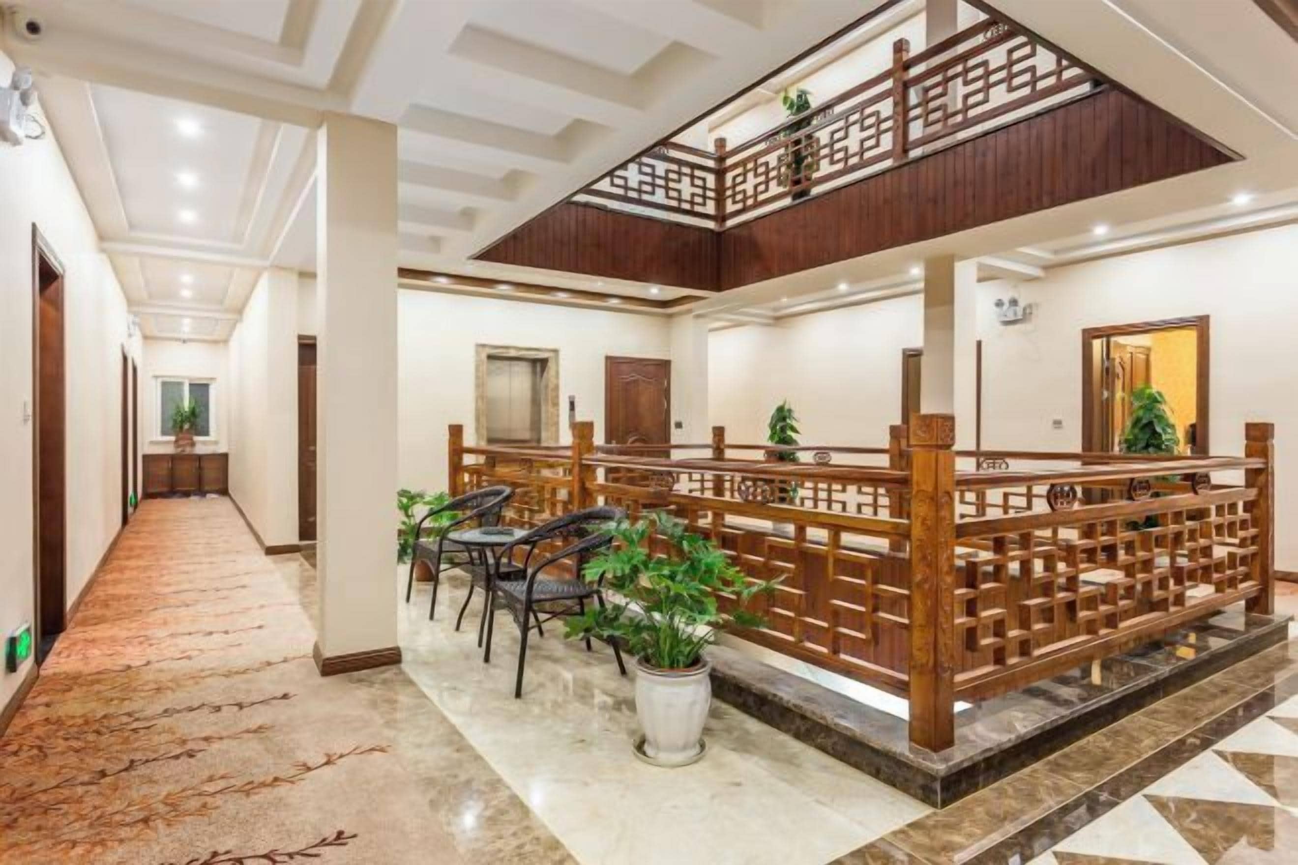 A hotel lobby with a central seating area, a staircase, and a reception desk.