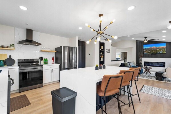 A modern kitchen with a central island, stainless steel appliances, and a contemporary light fixture.