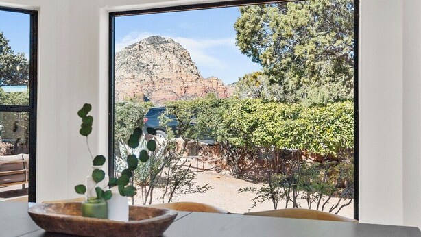 Un comedor con un amplio ventanal que ofrece vistas a un paisaje rocoso y vegetación.