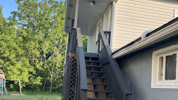 Una casa con una escalera de madera que conduce a un porche cubierto.
